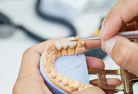 A dental technician working on a dental bridge