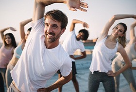 a man smiling while stretching with a group