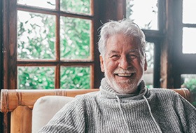 an older man smiling while sitting at home