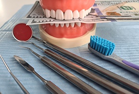 Mouth mold holding money next to dental instruments